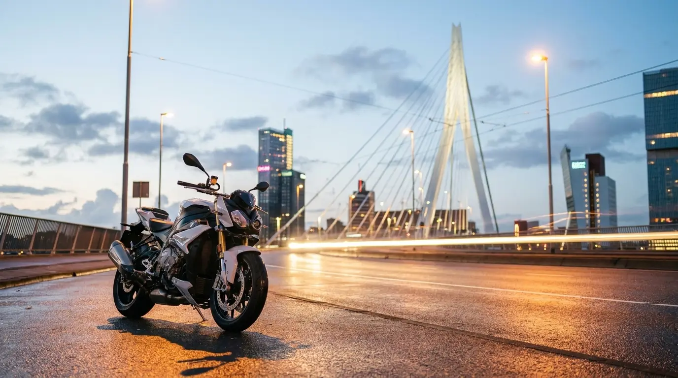 De iconische, verlichte Erasmusbrug die elegant in de achtergrond oprijst. — Een strakke, natgeregende asfaltweg op de Erasmusbrug met op de achtergrond de imposante, verlichte wolkenkrabbers van de Kop van Zuid.